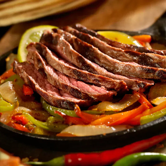 Charred steak fajitas with peppers and lime, showcasing a smoky Texas-style BBQ feast.
