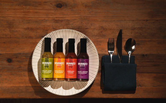 A bottle of Bravado Spice Co. Garlic & Árbol Moruga Scorpion Hot Sauce, featuring smoky garlic and chili flavor with bold red packaging.