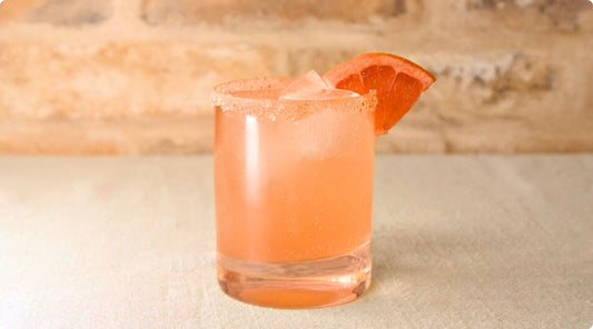 ruby red paloma cocktail in glass with grapefruit wedge on rim