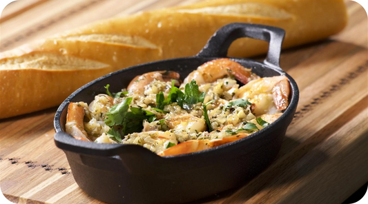 shrimp scampi in a skillet and french bread behind the skillet