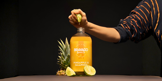 A man squeezes a lemon into Bravado Spice’s Pineapple and Jalapeno Margarita Mixer, with pineapple and lemon beside it.