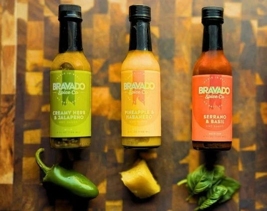 Three Bravado Spice hot sauces: Jalapeño, Habanero, and Serrano with their respective fresh ingredients.