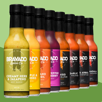 Row of Bravado Spice Co hot sauce bottles on a green background